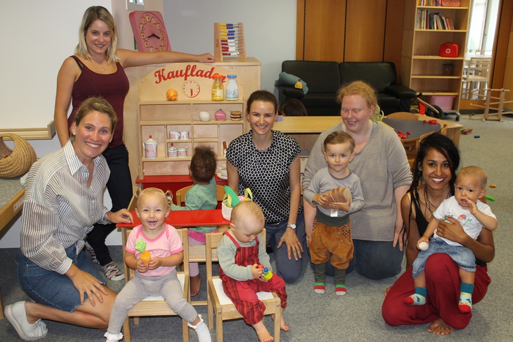 stv. Leiterin Lisa Geyer (sitzend links vom Kaufmannsladen) sowie Brigitte Baur (sitzend rechts vom Kaufmannsladen) freuten sich mit den Kindern und Eltern über die neuen Lebensmittel und Zubehör für den Kaufmannsladen
